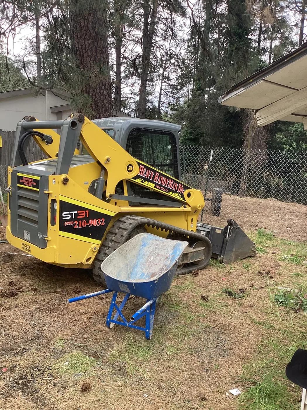 Perry's Landscaping skid steer parked on site with the company name and number on the boom