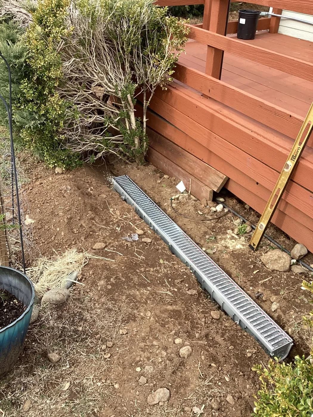 Channel drain and grate set along a fence line to carry surface water away