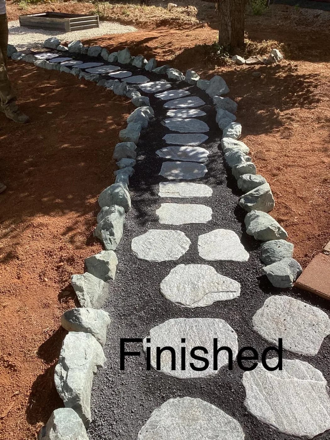 Flagstone stepping stones bordered with river rock winding across a mulched bed