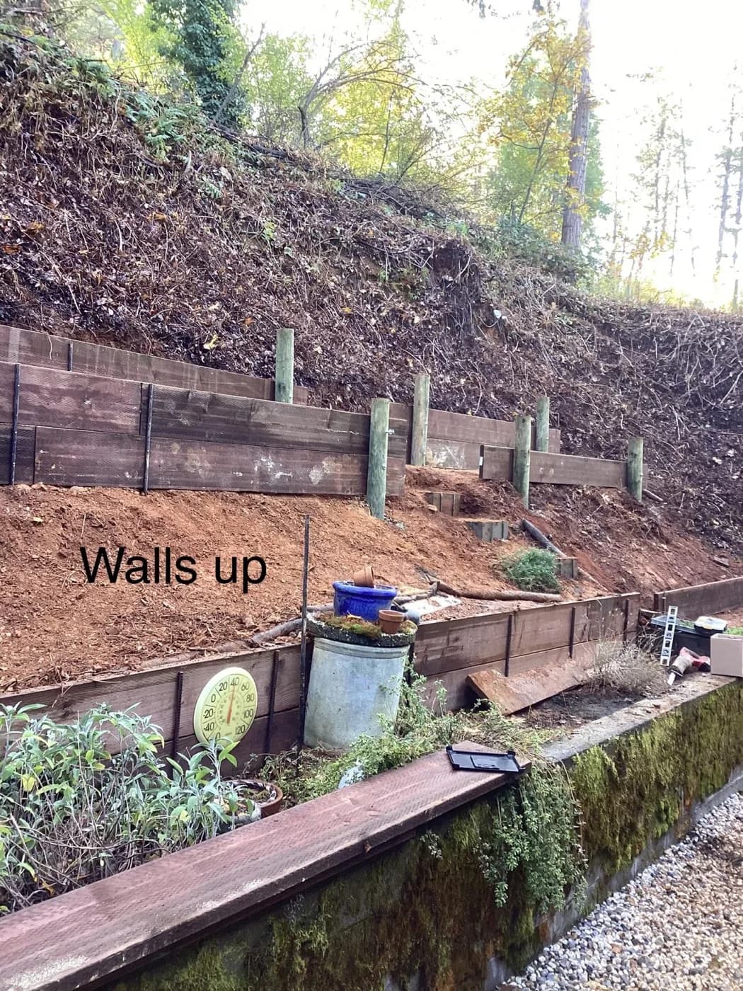 Timber retaining wall going up in tiers across a cut hillside
