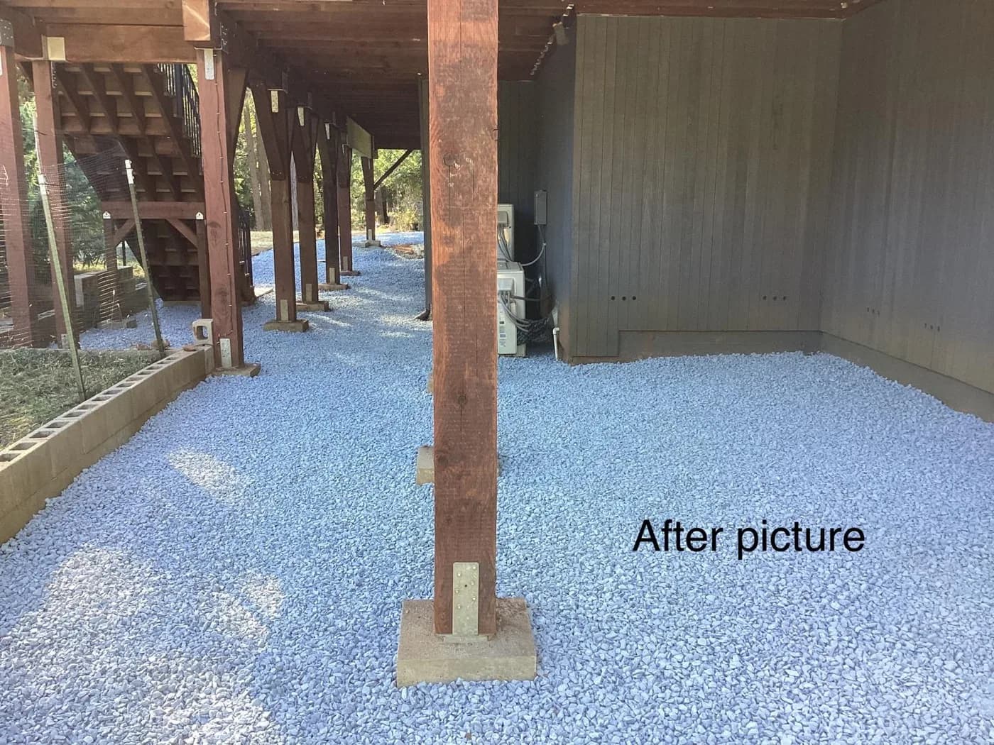 Drain rock spread under a raised deck after a French drain was installed