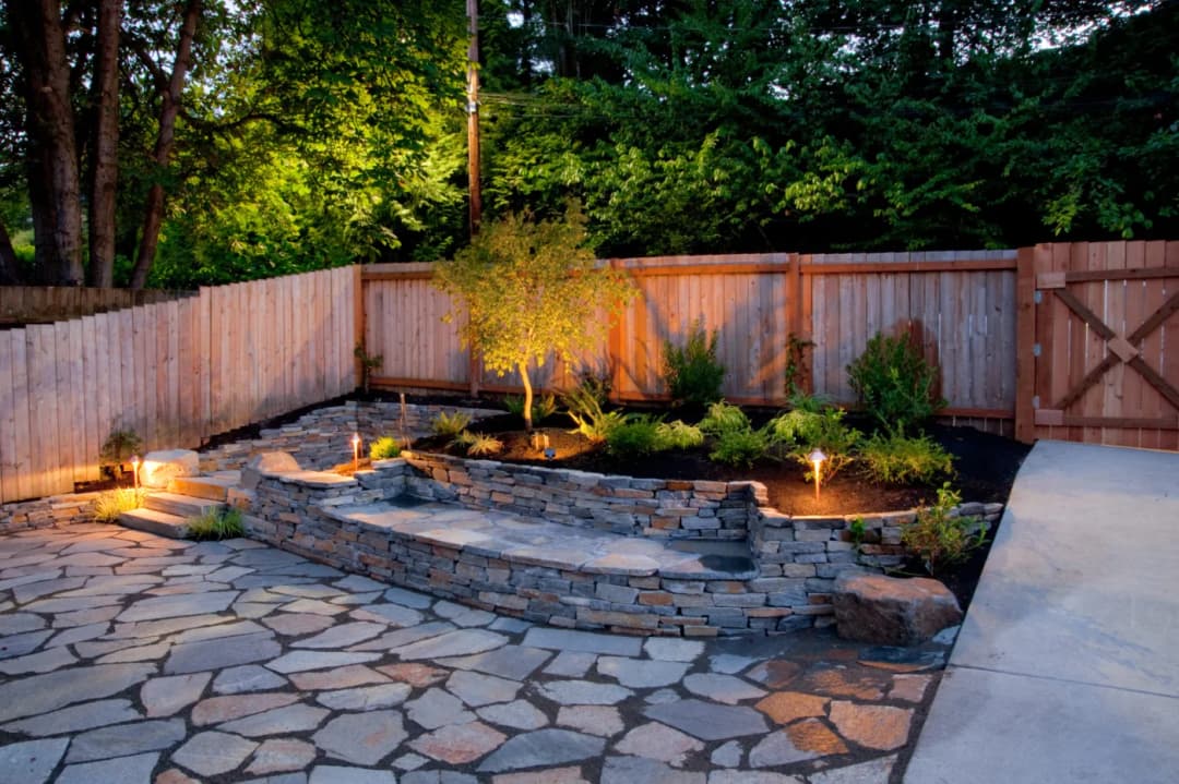 Flagstone patio with a dry-stacked stone wall and planted bed
